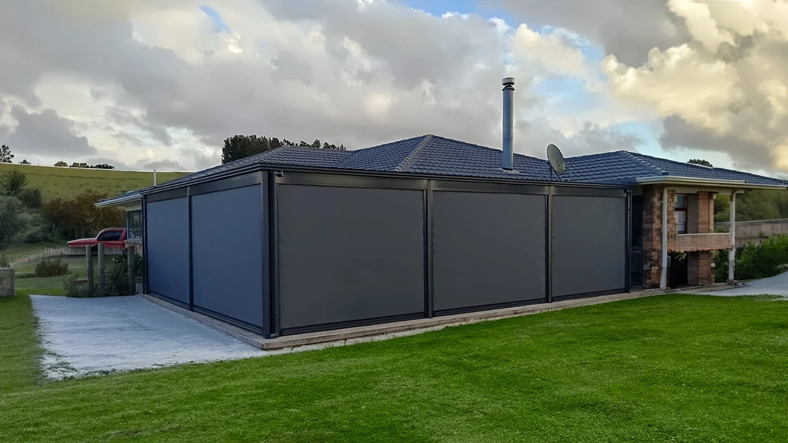 Multiple track-guided outdoor blinds fully lowered to completely enclose an outdoor alfresco entertaining area.